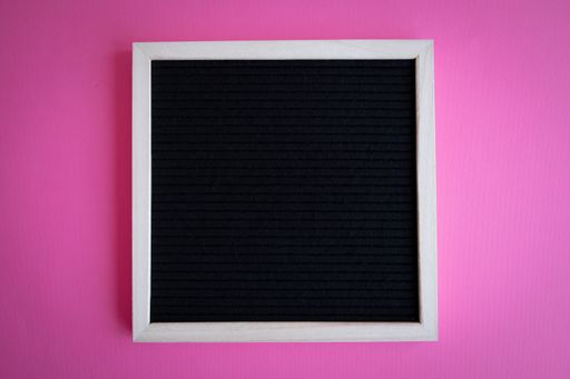 A top view shot of a blank blackboard with a white frame on a pink background with copy space