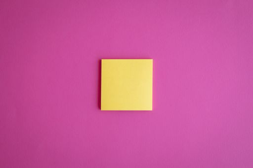 A top view of a yellow blank paper on a pink background with a copy space