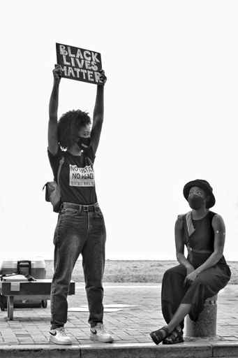 A grayscale shot of women protesting with a "Black Lives Matter" poster during the BLM protests in Busan, South Korea