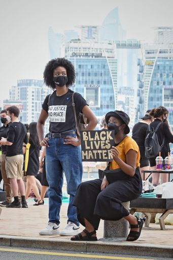 A vertical shot of women with a "Black Lives Matter" poster protesting during the BLM protests in Busan, South Korea