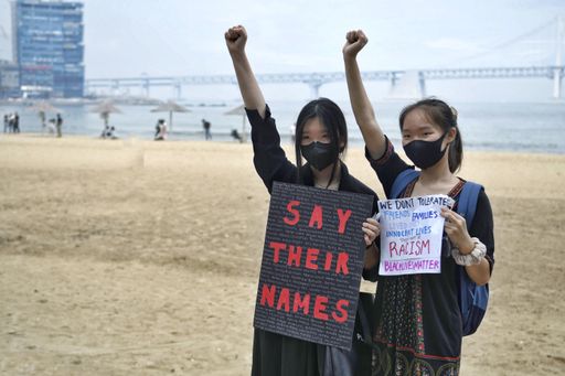 Two Asian women with posters protesting during the Busan BLM protests in South Korea