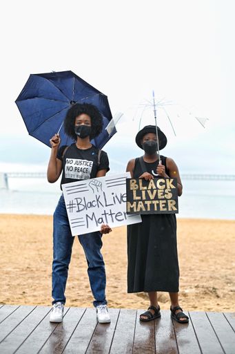 Two black female protesters holding banners with a sign "Black lives matter"