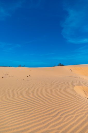 A vertical image of the beautiful sand dunes of Mui Ne, Vientam under a clear blue sky