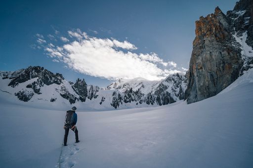 An alpinist on a glacier walking towards big alpine mountain. Climber on a alpine ascent in Mont Blanc massif near Chamonix, France. High alpine lands