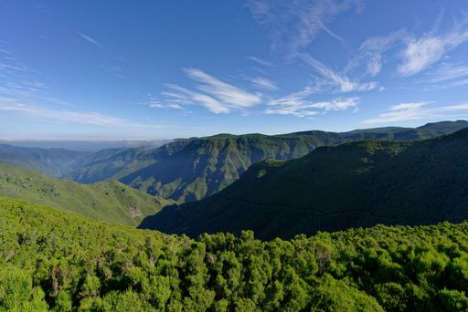 A distant landscape shot of green hills and mountains under a sunny sky
