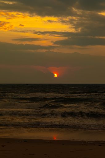 A vertical shot of the sea with the sun shining behind the clouds in Vietnam
