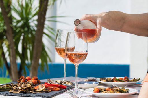 a hand of woman pouring rose wine during a family party of a lunch. lifestyle concept