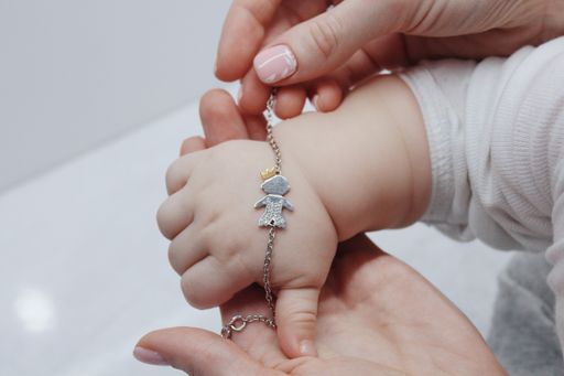 A closeup shot of a female putting a cute bracelet on her baby's hand