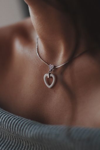 A closeup shot of a female wearing a beautiful silver necklace with a pendant