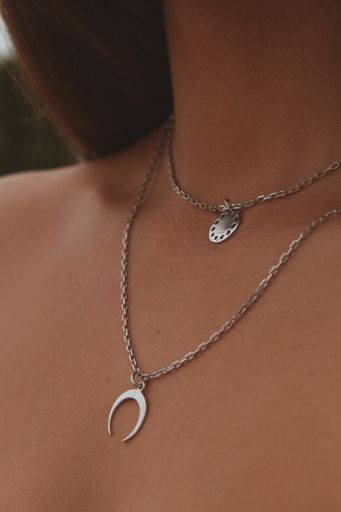 A vertical closeup shot of a female wearing a silver necklace with beautiful pendants