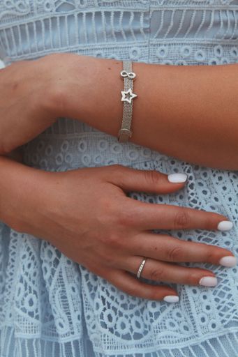 A closeup shot of a female in a blue dress wearing a beautiful silver bracelet and a ring