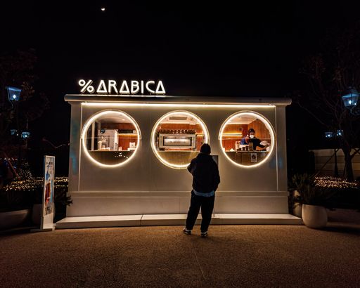 Coffee shop Arabica brand illuminated at night.