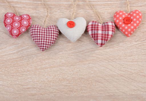 A top view of small heart-shaped cushions on a wooden surface with space for text