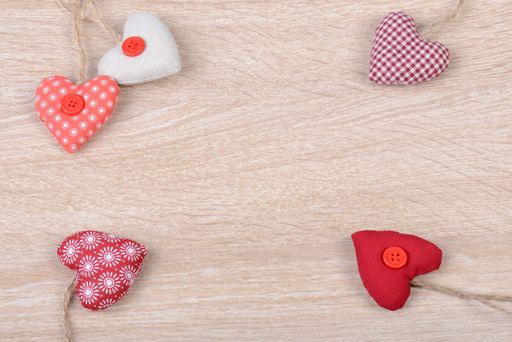 Various heart-shaped ornaments in the corners of a wooden background with copy space in the middle