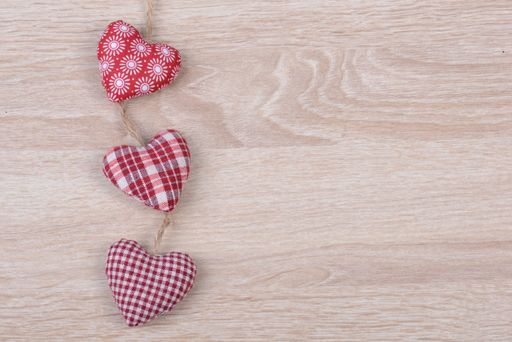 A top view of small heart-shaped cushions on a wooden surface with space for text