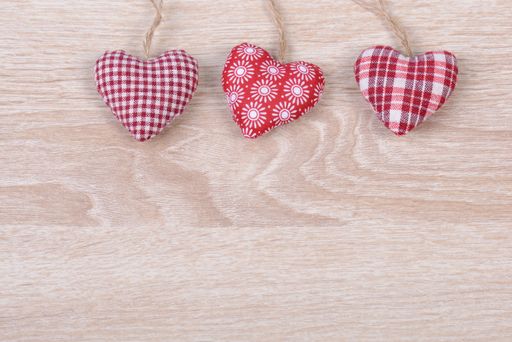 A top view of small heart-shaped cushions on a wooden surface with space for text