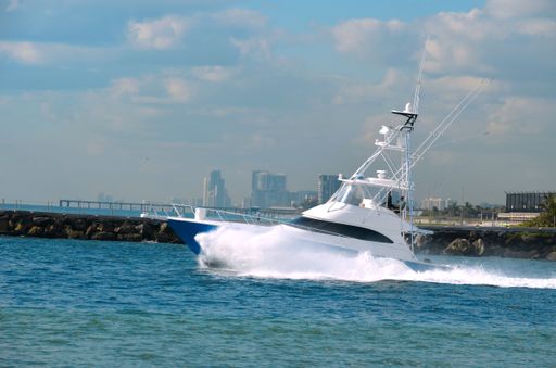 A closeup shot of a small yacht moving in the water near the shore