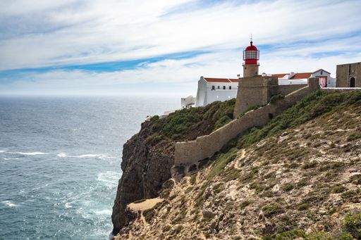 A beautiful shot of a red lighthouse on the cliffs of Cape St. Vincent in Algarve Portugal