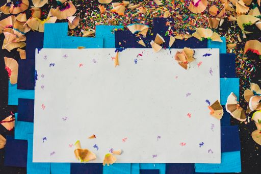 A backdrop of white paper for your text with colorful pencils sharpening waste on the frame