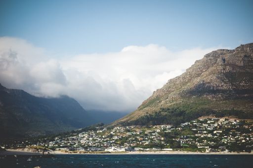 A beautiful wide shot of Cape town at the bottom of mountains near a sea under a clear sky