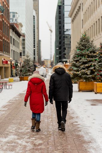 A vertical shot of two people walking on a snowy street in the city centre during the Christmas season