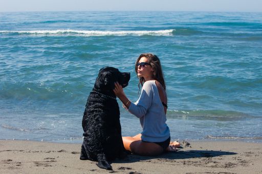 young woman with her dog at sandy sea beach enjoy in summer day
