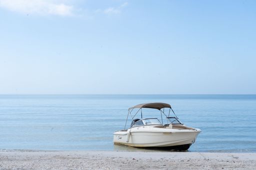 A serene beach scene with a small boat anchored on the calm shore under a clear blue sky.