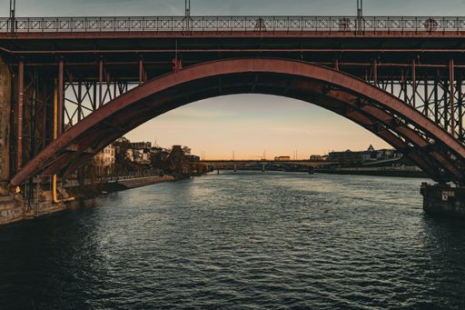 A shot of the river under the red bridge under a golden sky at sunset in Maribor, a beautiful city in Slovenia.