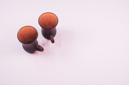 a high angle shot of two empty cups of coffee on a white surface