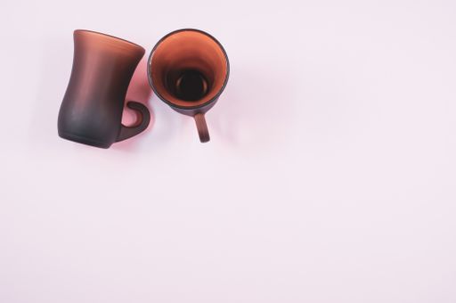 A high angle shot of two empty cups of coffee on a white surface