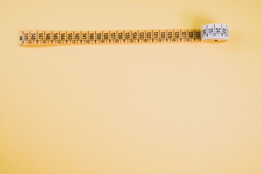 A high angle shot of a measuring tape on a yellow surface