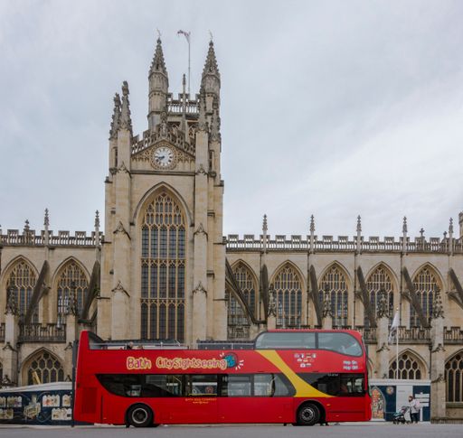 The Abbey of Bath with sightseeing open-topped red double-decker bus, United Kingdom