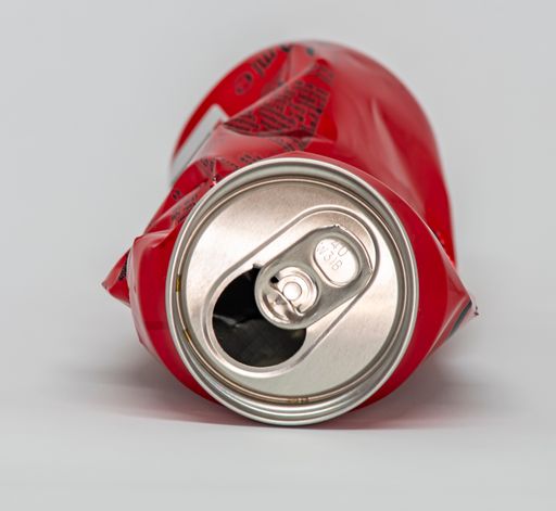 A crushed red cola can isolated on a white background