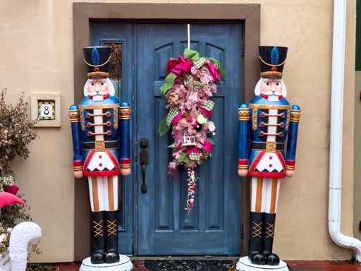 Festive nutcracker statues flank a decorated door with a colorful wreath, creating a charming holiday entrance.