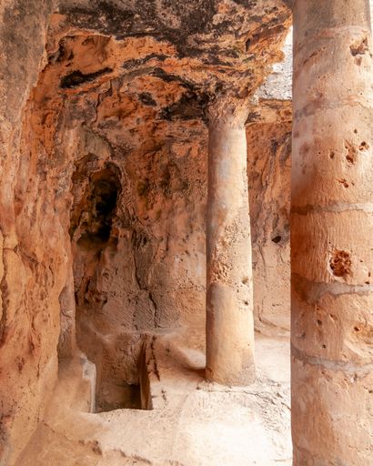 Ancient rock-cut tombs with columns in Paphos, Cyprus, showcasing historical architecture and archaeological significance.