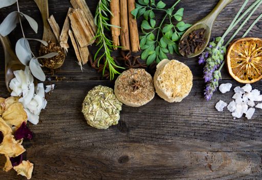 A rustic arrangement of dried herbs and spices on a wooden table, featuring cinnamon, rosemary, and dried citrus slices.