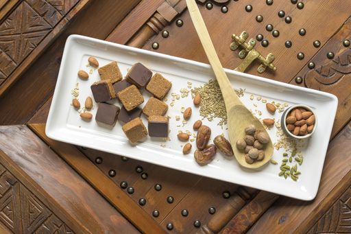An overhead shot of different types of nuts and square-shaped nuts on a wooden decorative surface