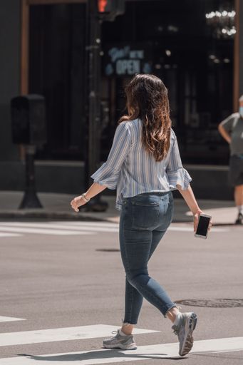 A vertical shot of a young stylish female crossing the street