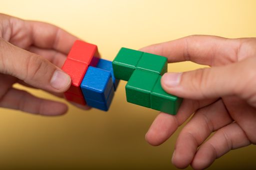 A closeup of the hands holding colorful pieces of block puzzle.