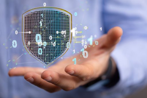 The hand holding a 3D rendered hologram of a shield with binary numbers.