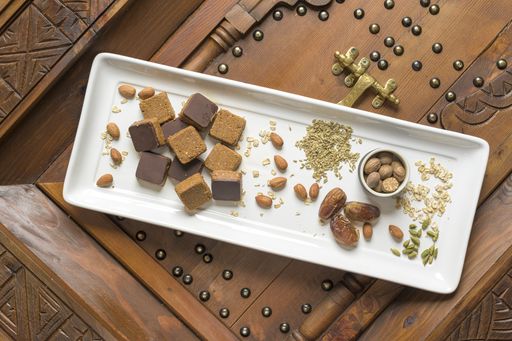 An overhead shot of different types of nuts and square-shaped nuts on a wooden decorative surface