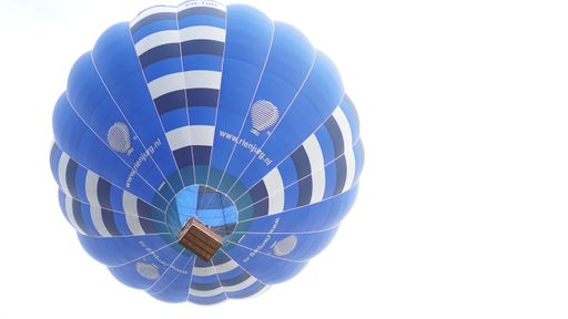 A vibrant blue hot air balloon soaring against a clear sky, viewed from below.