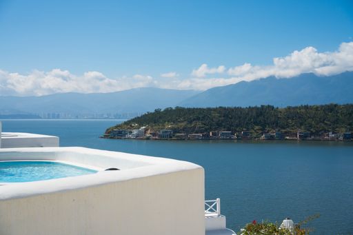 A luxurious terrace view with a hot tub, blue bay, islands, and distant mountains.