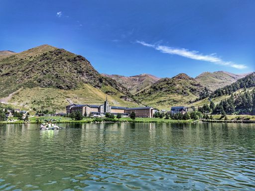 The beautiful view of the lake with buildings and mountains in the background. Vall de Nuria, Spain.