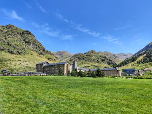 The beautiful view of the green valley with buildings and mountains in the background. Vall de Nuria, Spain.
