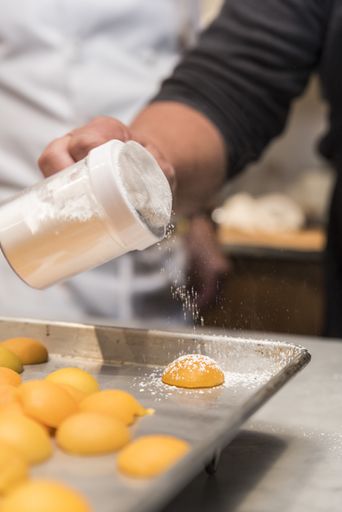 A closeup shot of a chef working with eggs and making something in the kitchen of a cafe