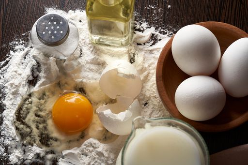 A closeup shot of fresh eggs, oil, salt, milk, and flour prepared for baking