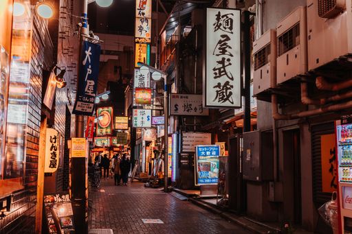 A cobble street lined with illuminated shops at night in Japan
