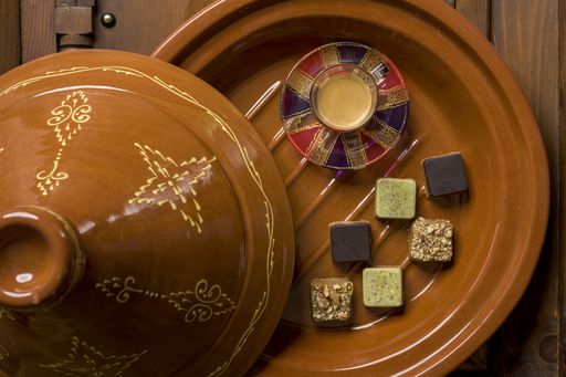 An overhead shot of different types of square-shaped sweets with tea on a wooden tray