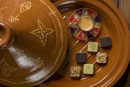 An overhead shot of different types of square-shaped sweets with tea on a wooden tray